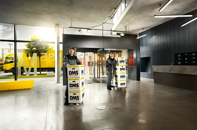 Transport von Umzugsboxen durch die Eingangshalle eines Bürogebäudes
